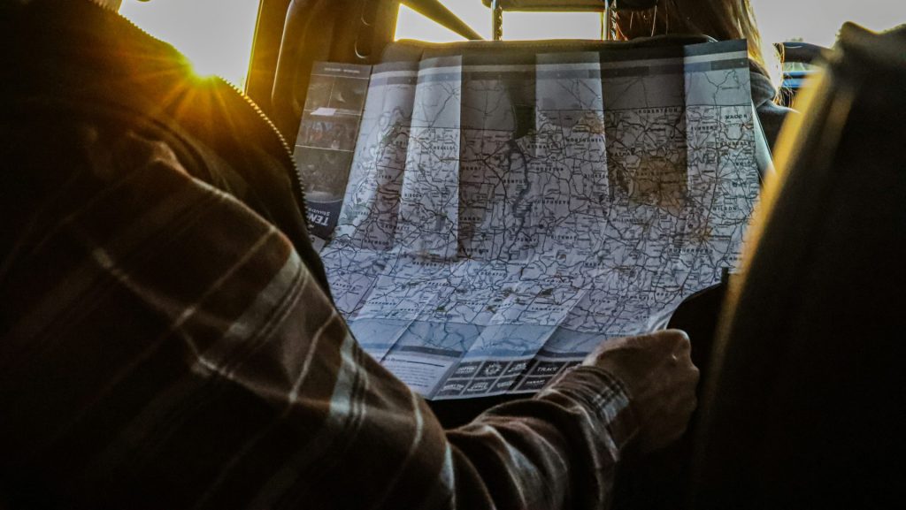 Man studying a map in a car at sunset